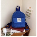 Macro-opname van blauwe corduroy mini-rugzak met wit logo-label op een houten plank - Saffierblauw