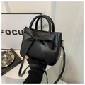 Detail of black faux leather handbag with oversized bow and gold metallic hardware - Black