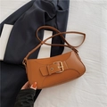 Warm brown faux leather shoulder bag with decorative gold buckle shown in a lifestyle view - Brown