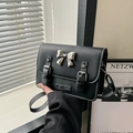 Black crossbody bag with silver bow accent and white contrast stitching detail - Black