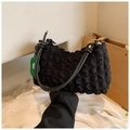 Detailaufnahme einer schwarzen Tasche mit Blasenstruktur und grünem Blumenanhänger - Schwarz