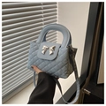 Detail van lichtblauwe gewatteerde minitas met zilveren metalen strik en handvat boven - Blauw