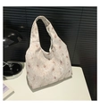 Détail du sac cabas en toile beige avec motif floral blanc posé sur une table blanche - Kaki