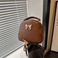 Brown woven leather backpack with a gold bow accent and versatile shoulder straps - Brown