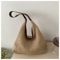 Close-up of hand-woven straw tote bag with brown leather shoulder straps on a wooden table - Brown
