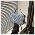 Détail du sac à main matelassé bleu clair avec barre métallique dorée et anse - Bleu