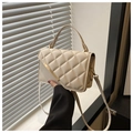 Détail d'un sac à main matelassé blanc crème avec garniture en métal doré tenu par un modèle - Blanc Cassé