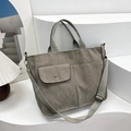 Detailed close-up of grey-green corduroy tote bag featuring front pockets and adjustable strap - Light Gray