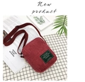 Detail view of burgundy corduroy crossbody bag with adjustable strap on rustic background - Red