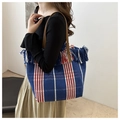 Detail of colorful striped canvas tote with fringe trim and leather handles on model - Blue