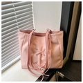 Close-up of light pink leather tote bag featuring a decorative bow and lace-up details - Pink