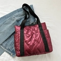 Quilted burgundy puffer tote bag with glossy finish and black handles on white background - Red