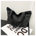 Détail de la texture d'un sac cabas en denim noir et de sa bandoulière large - Noir