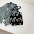 Black tote bag with colorful wave embroidery shown with a blue denim jacket - Black