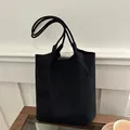 Sac seau minimaliste en daim noir avec double bandoulière sur présentoir en bois - Noir