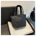 Gros plan d'un cabas noir à texture cuir froissé sur soie blanche en coffret cadeau - Noir