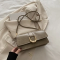 Sac bandoulière en cuir marron texturé avec boucle dorée sur une veste beige - Kaki