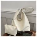 Dettaglio del set borsa tote in pelle color crema con pochette coordinata su tavolo in legno - Bianco