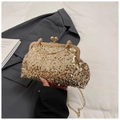 Detailed close-up of golden sequin evening clutch bag with round metal handle and clasp - Gold