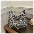 Chic leopard print canvas tote bag in black and brown on a wooden coffee table - White