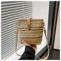 Détail du sac seau en paille tressée avec bandoulière en cuir et boucle dorée chic - Kaki