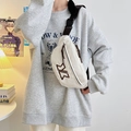White canvas crossbody bag with brown embroidery and adjustable strap on a female model - White