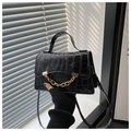 Detail der schwarzen Handtasche mit Krokodilstruktur, Goldkette und Glanzfinish - Schwarz