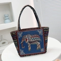 Ethnic blue embroidered elephant tote bag with colorful striped handles on a table - Blue Side Elephant
