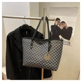 Vista detallada de bolso tote con estampado M y colgante dorado junto a un blazer negro - Negro