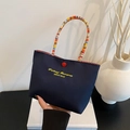 Dark blue handbag with yellow letter embroidery and colorful woven handle detail - Blue