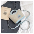 Detail of hand-woven straw bag with light blue leather handles and lace bow accents - Blue