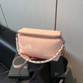Borsa a tracolla rosa con stampa serpente e catena argentata su divano nero - Rosa