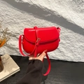Minimalist red leather saddle bag with gold buckle displayed on a textured stone background - Red