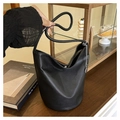 Minimalistische zwarte bucket bag van kiezelleder met zilveren ketting op houten blad - Zwart