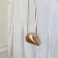 Detailed close-up of golden shell shaped metal clutch bag with spiral texture and chain - Gold