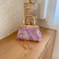 Detalle de texturas florales 3D en color lavanda y cierre dorado en bolso de noche elegante - Púrpura