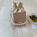 Detalle de bolso saco de jacquard rosa con elegante asa de perlas y cierre de cordón - Rosa