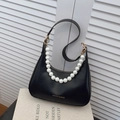 Black leather hobo bag with white pearl chain and golden hardware on decorative book - Black