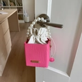 Pink woven mini bucket bag with pearl handle and white drawstring lining on a door handle - Pink