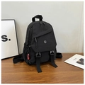 Detail of black nylon backpack featuring metal M logo and stylish red fashion charm tag - Black
