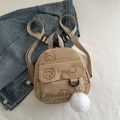 Mini beige corduroy backpack featuring black smiley face prints and a plush ball charm - Khaki