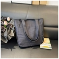 Detailopname van zwarte canvas shopper met geweven label op een lederen bankstel - Blauw