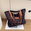 Sac cabas noir en toile à imprimé cerise avec poignées en cuir marron sur un magazine - Noir