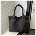 Detailed close-up of a black nylon tote bag featuring side drawstrings and woven rope charm - With Pendant / Black
