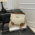Bolso cubo bicolor en crema y marrón con correa ancha sobre un fondo minimalista moderno - Blanco