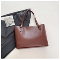 Detail van een bruine leren shopper met gouden letters en verstelbare gesp aan riem - Bruin