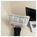 Close-up of white quilted puffer clutch bag being held in a clean lifestyle setting - White