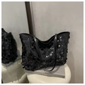 Black sequined tote bag with leather straps and gold rivets on a white display stand - Black