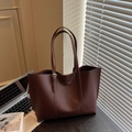 Dunkelbraune matte Leder-Einkaufstasche mit Goldlogo in einer eleganten Büroumgebung - Kaffeebraun