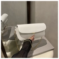 Detail van witte laklederen baguette tas met gouden gesp en een metalen ketting - Wit
